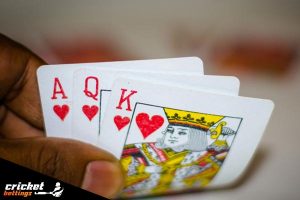 man's hand holding cards and playing teen patti game